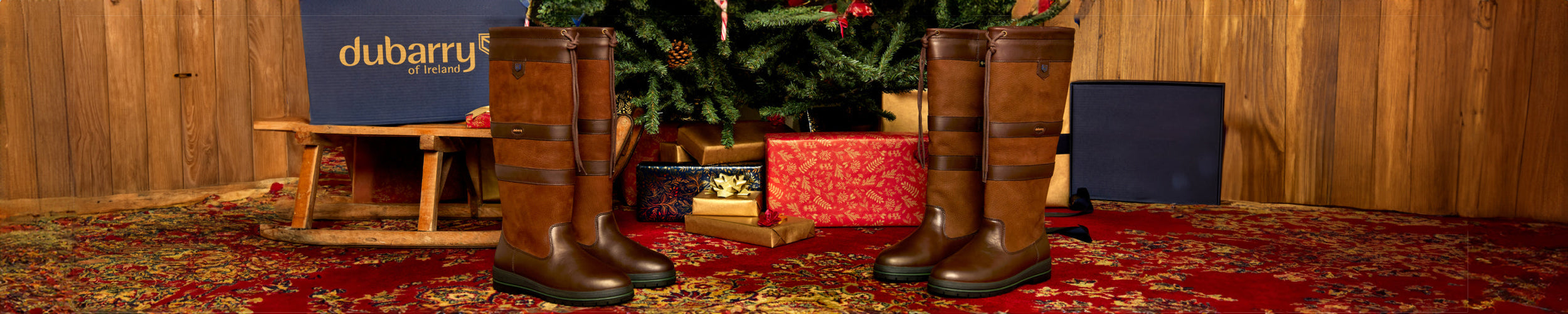 Wide Image of a pair of Galway Leather Waterproof Breathable Country Boots positioned in front of a Christmas tree, with one pair on each side, creating a festive setting.