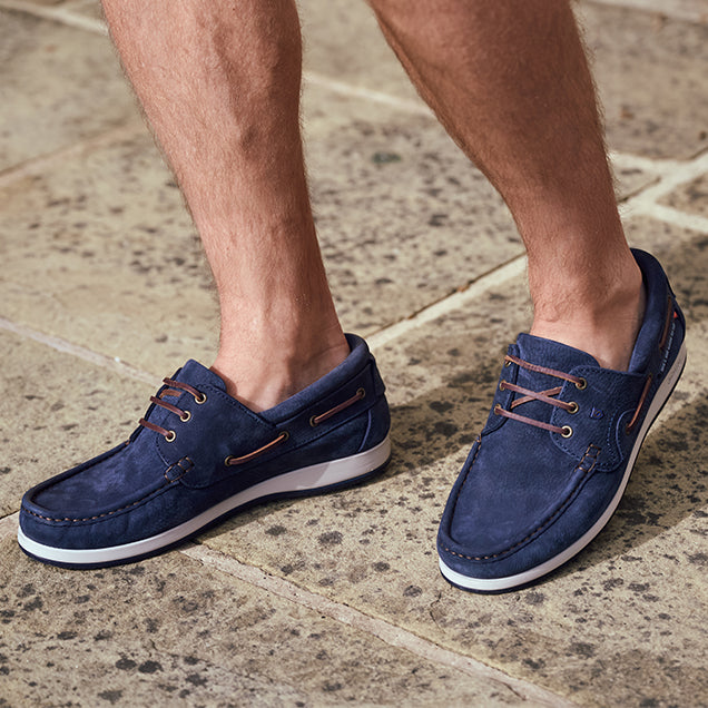 Dubarry Navy blue suede shoes with white soles on a stone pavement
