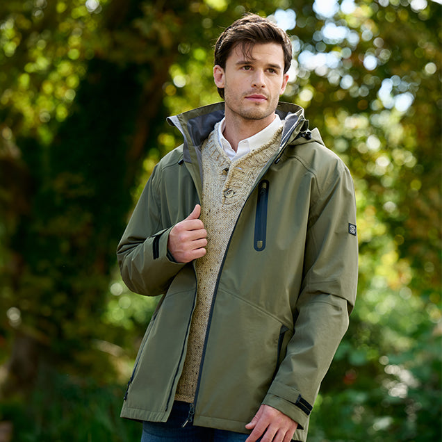Man wearing a Dubarry green jacket with a fur-lined hood outdoors