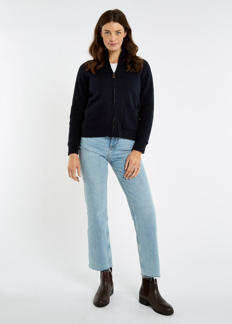 Woman wearing a navy full zip knit sweater with jeans and brown ankle boots