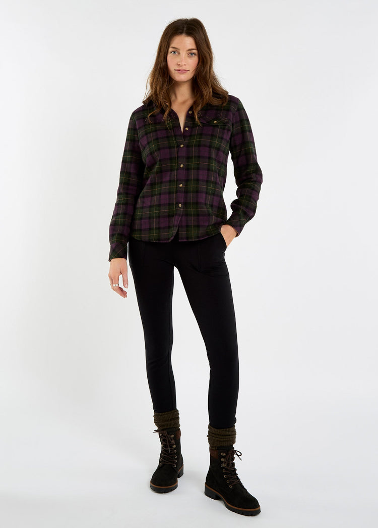 Woman modelling black leggings with a dark plaid shirt and brown lace up boots